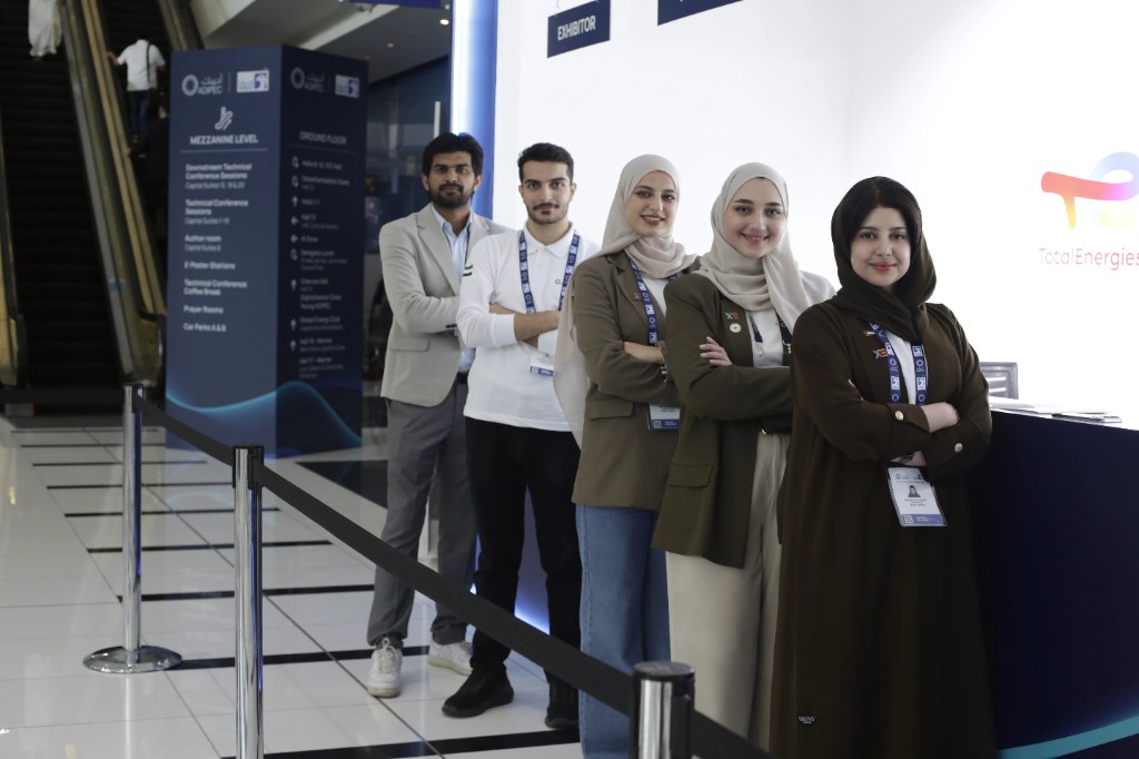Front-of-house team in ADIPEC lanyards at a registration zone inside ADNEC