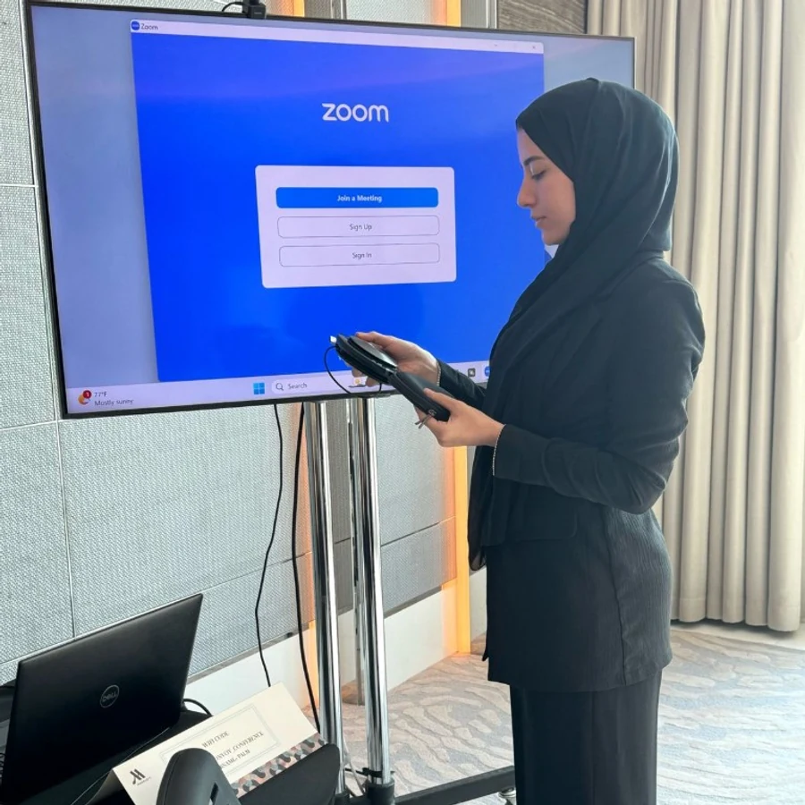 Event coordinator setting up AV and Zoom for a hybrid meeting room
